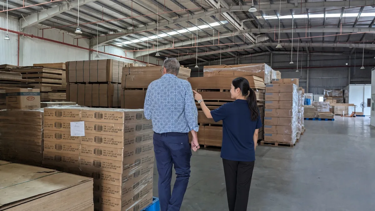 A buyer and a sourcing specialist inspecting pallets of stock inside a warehouse